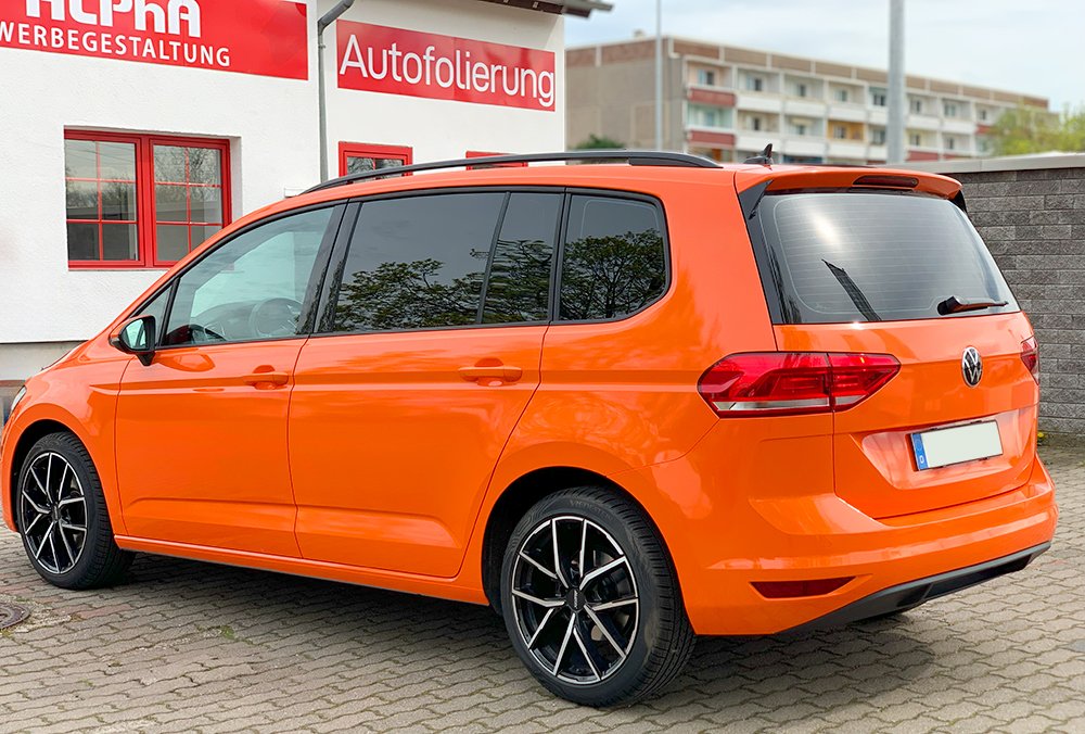 Vollfoliertes oranges Auto vor Firma